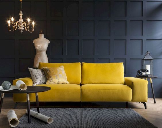 parete a boiserie blu scura con divano giallo