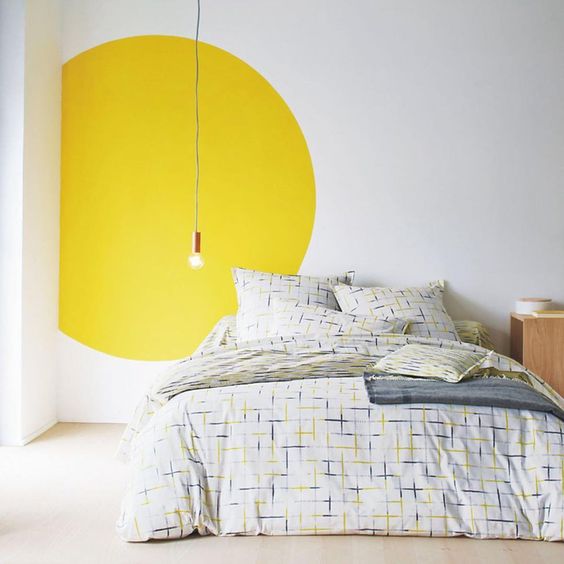 camera da letto: la lampadina scende dal soffitto, non è presente una testata e si enfatizza il tutto con un cerchio giallo che mette in risalto il punto luce